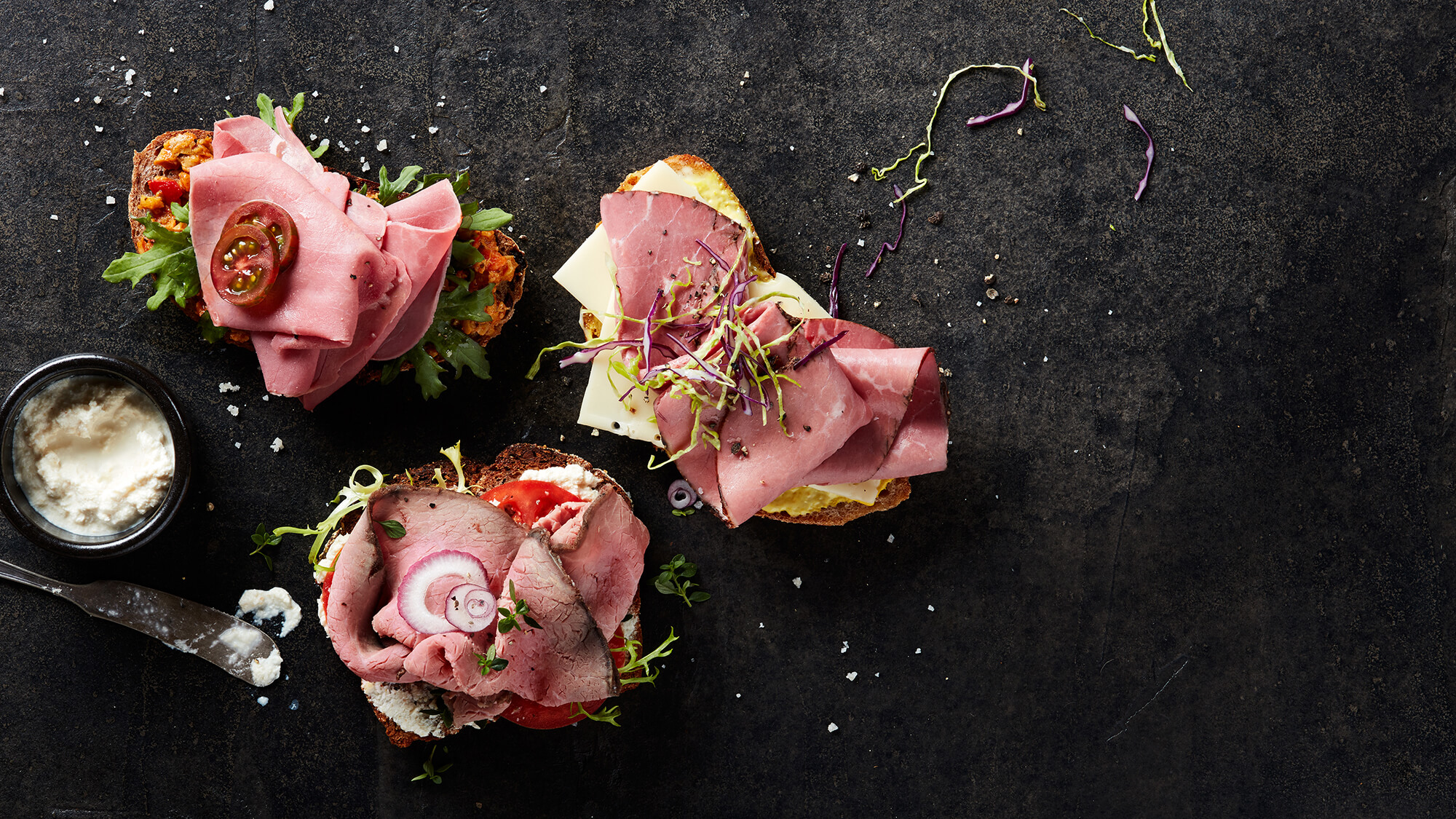 Three gourmet deli meat sandwiches made from Columbus Corned Beef, Roast Beef, and Pastrami with horseradish sauce on the side